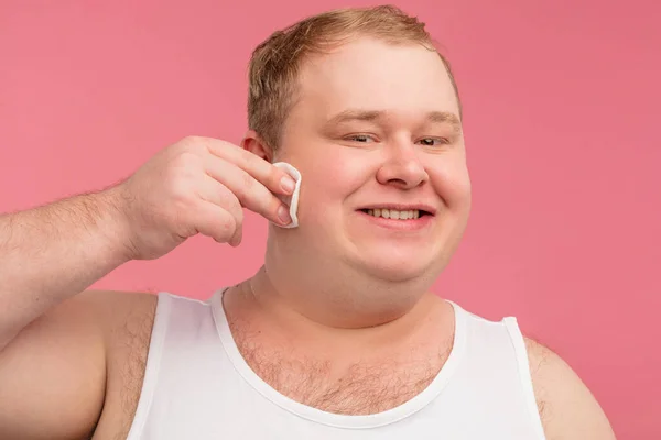 Heureux homme gai tient des tampons de coton et essuyer sa peau avec de la lotion — Photo