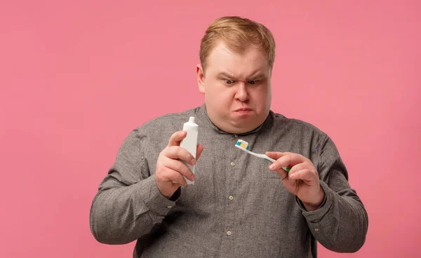 Emocionální nespokojenost a zmatený muž čistí zuby s novou zubní pastou. — Stock fotografie