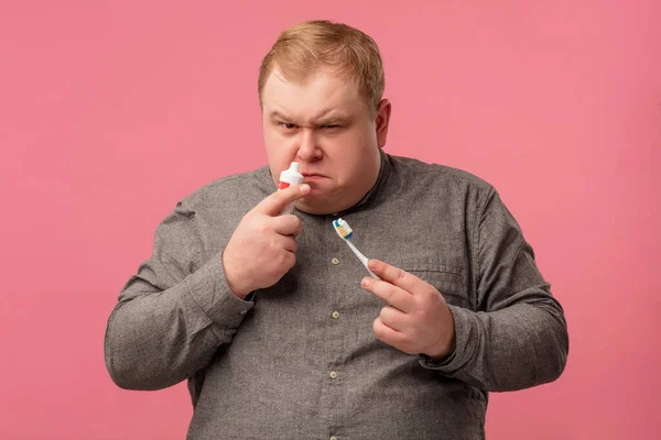 Persona alérgica sobresaltada, cepillarse los dientes con pasta nueva, mirando sorprendido. — Foto de Stock