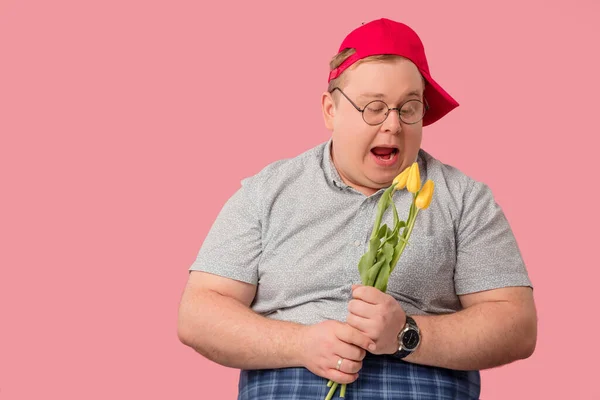 Uomo comico in berretto rosso con tulipani gialli con sguardo sorpreso stupito. — Foto Stock