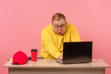 Komik suratlı, parlak günlük giysili yakışıklı bir adam bilgisayarla çalışıyor.