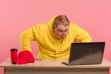 Şişman vücutlu şok olmuş bir adam ağzını açar ve dizüstü bilgisayarına bakar..