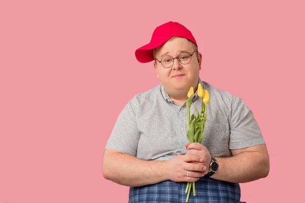 Zögerlicher molliger Mann wartet auf Freundin mit Blumen auf rosa Hintergrund — Stockfoto