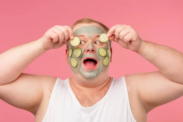 Alegre hombre divertido tiene máscara de arcilla, expresa emociones positivas, aislado en rosa. — Foto de Stock