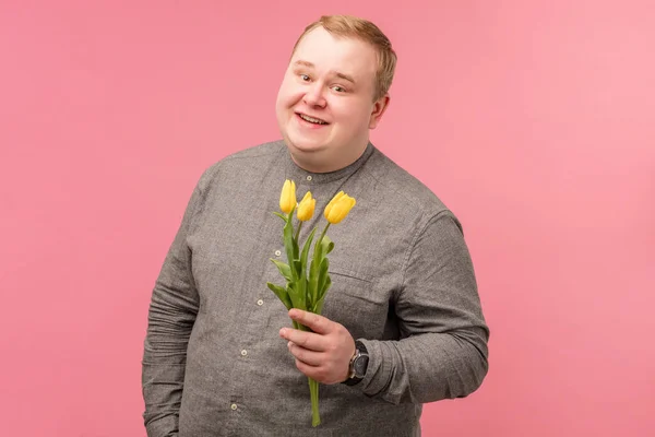 Feliz hombre tubby sonriendo sosteniendo flor mientras piensa listo para el día de San Valentín —  Fotos de Stock