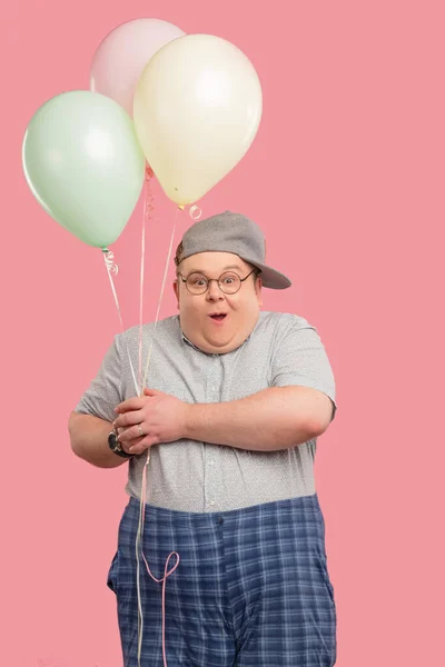 Grappige tubby kerel met positieve emoties vrolijk glimlachen, houden luchtballonnen. — Stockfoto