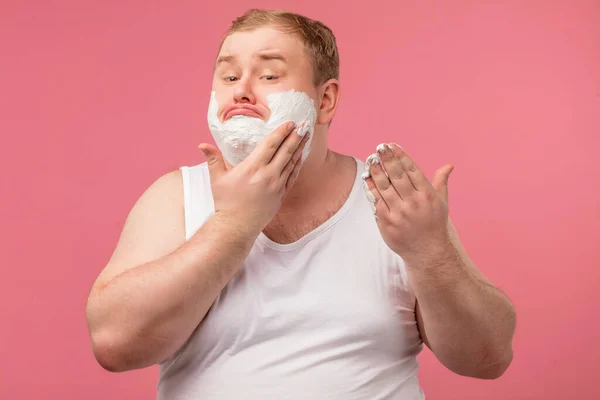 Homem da manhã com espuma nas bochechas, tem expressão desagradada triste, cansado de barbear — Fotografia de Stock