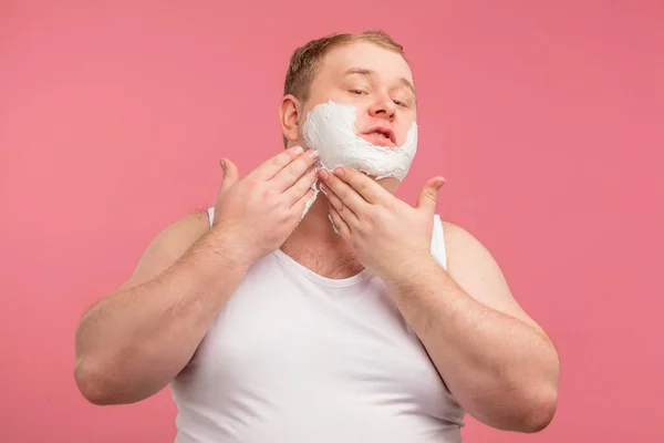 Feliz hombre regordete con espuma de afeitar en su cara y afeitadora aislado en rosa — Foto de Stock