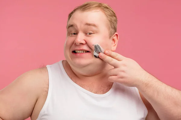 Feliz homem gordo com espuma de barbear em seu rosto e navalha isolada em rosa — Fotografia de Stock