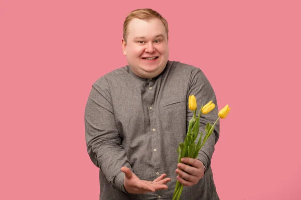 Uomo divertente con fiori che vanno a fare la proposta, ha un aspetto allegro e sorriso ingenuo — Foto Stock