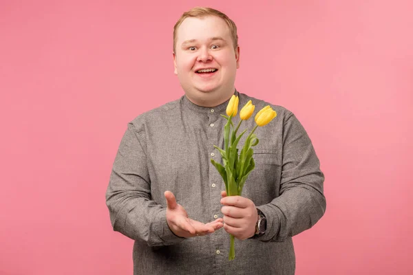 Homem engraçado com flores vai fazer proposta, tem olhar alegre e sorriso ingênuo — Fotografia de Stock