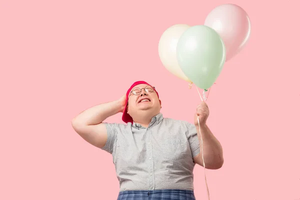 Glücklicher Mann in kindlichem Gewand, der fröhlich lacht, während er Luftballons in der Hand hält — Stockfoto