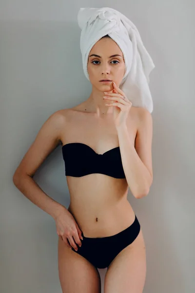 Mujer en lencería negra posando con toalla en la cabeza sobre fondo claro —  Fotos de Stock