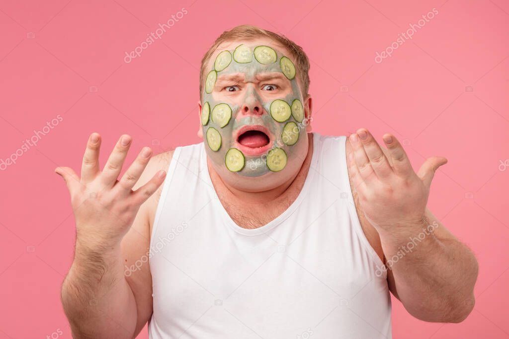 Desperate man being angry as cucumber mask irritate his sensual skin
