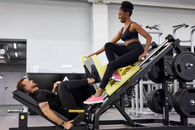 Spor salonundaki atletik insanlar birbirlerini destekliyor, birlikte egzersiz yapıyorlar.