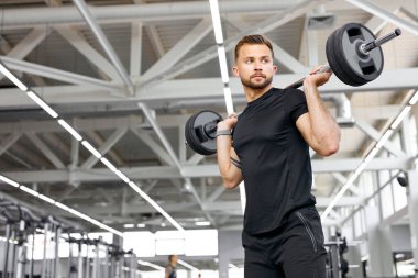 güçlü ve kaslı bir adam halter kaldırma egzersizi yapıyor.