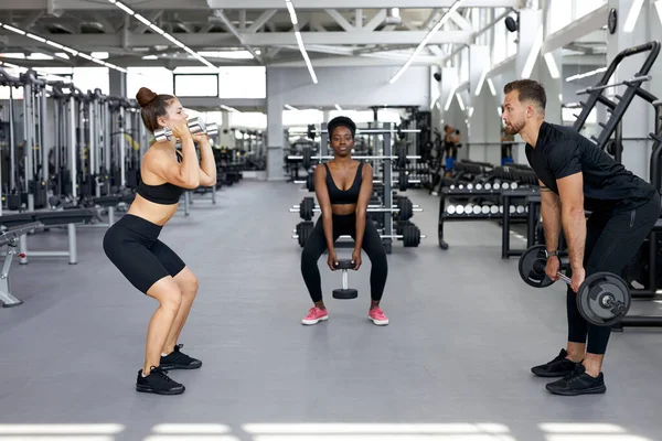 Idrottare, multietnisk grupp utföra övningar med tunga vikter i gymmet — Stockfoto