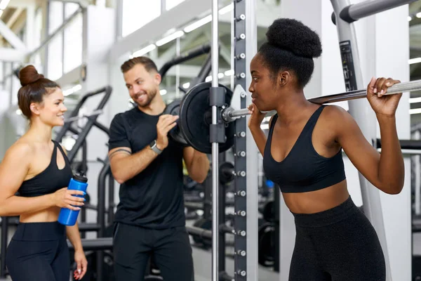 Twee atletische diverse vrouwen praten met trainer in de sportschool — Stockfoto