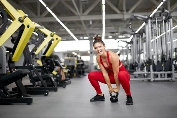 Ung flicka gör övningar med en vikt i gymmet — Stockfoto