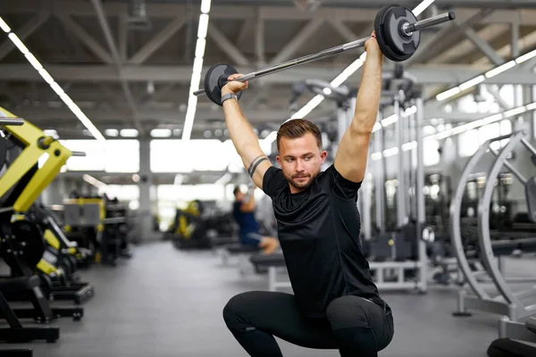 Kaukasisk atletisk man som pumpar upp muskler med skivstång — Stockfoto