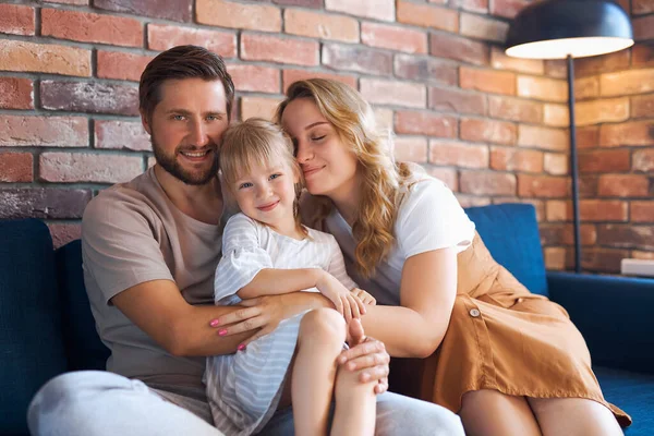Retrato de linda família com filha no sofá em casa — Fotografia de Stock
