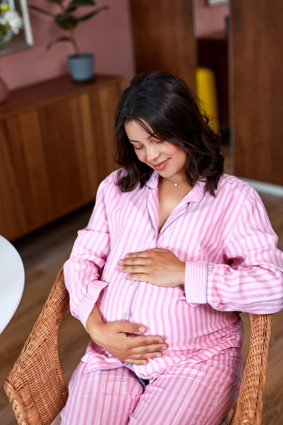 Linda mujer embarazada toma de la mano en el vientre en casa — Foto de Stock