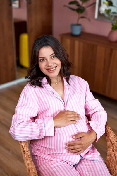 Carino donna incinta tiene le mani sulla pancia a casa — Foto Stock