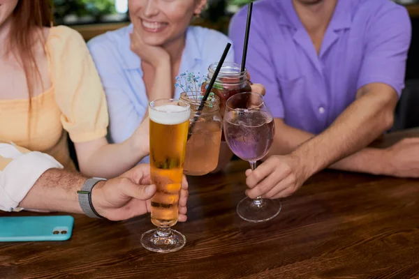 Grupo de jóvenes tintinean vasos con bebidas en restaurante o bar — Foto de Stock