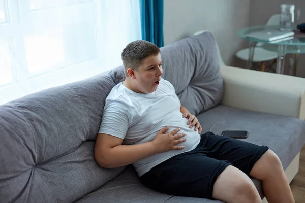 fat teenager boy has stomach ache after junk food