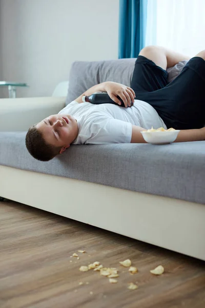 Comer en exceso niño gordo dormir en el sofá en la sala de estar —  Fotos de Stock