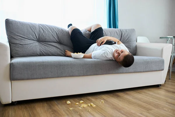 Comer en exceso niño gordo dormir en el sofá en la sala de estar —  Fotos de Stock