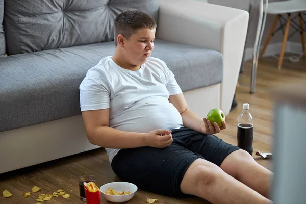 Un niño con sobrepeso disfruta llevando un estilo de vida pasivo poco saludable — Foto de Stock