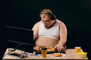 Evde bilgisayar oyunu oynayan kulaklıklı komik bir genç adam.