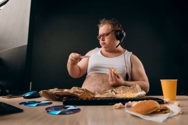 Obez adam kahvaltı yaparken izlemek için diski seçiyor.