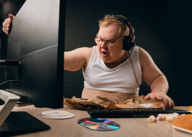 Öfkeli ve öfkeli bir adam evde bilgisayarla oturuyor.