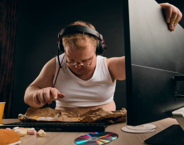 Mutsuz şişman adam bilgisayarı tamir etmeye çalışıyor.