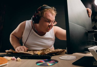 Şişman adam fast food yiyor ve çiğniyor.