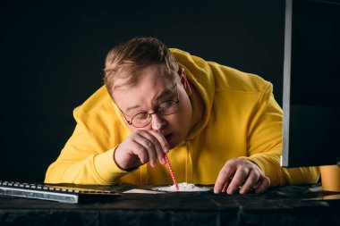 Adam masanın arkasında otururken uyuşturucu çekiyor.