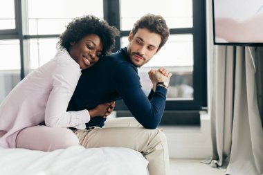 Irklar arası genç çift yatakta rahatlıyor ve eğleniyor. Afrikalı kadın
