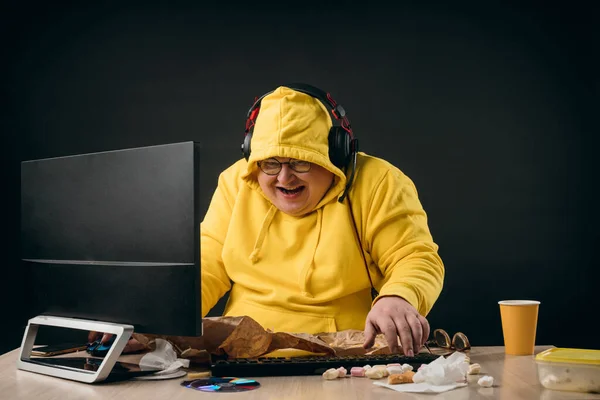 Pozytywny człowiek śmieje się z czegoś siedząc przed komputerem — Zdjęcie stockowe