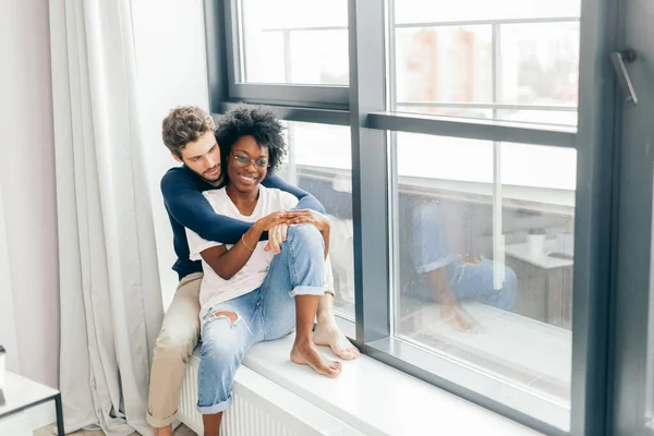 Romantisch gemengd ras paar staan bij het raam denken over hun toekomst. — Stockfoto