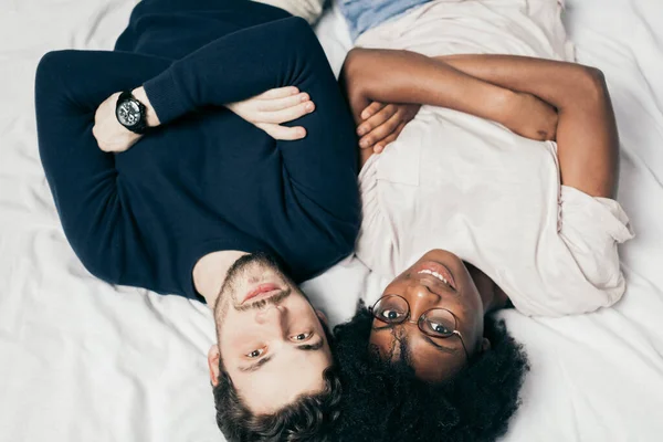 Retrato de casal feliz, vestido casualmente, deitado na cama no quarto — Fotografia de Stock