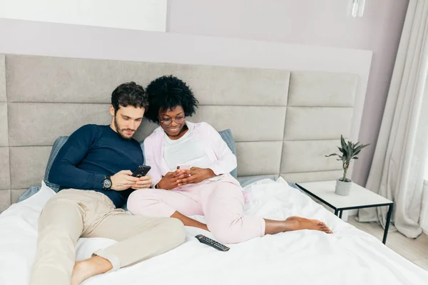 Amerikaanse man delen van foto 's met zijn mooie Afrikaanse vriendin in de slaapkamer — Stockfoto