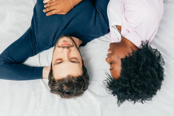 Casal jovem dormindo juntos na cama no quarto, abraçando uns aos outros docemente — Fotografia de Stock