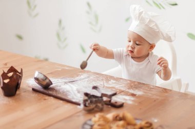 Mutfakta küçük komik aşçı kurabiye keskisi ve unla oynuyor.