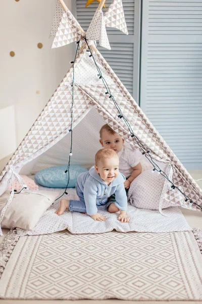 Oyuncak çadırda, oyun odasında oynayan iki çocuk, yuvarlanmayı öğreniyorlar.