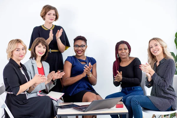 Equipo femenino multiétnico aplaudiendo durante seminario de negocios en sala de conferencias — Foto de Stock