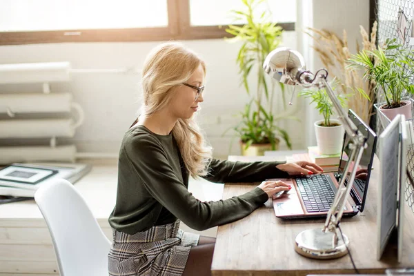 Donna bionda sorridente seduta sulla sedia dell'ufficio. Giovane assistente sul posto di lavoro — Foto Stock