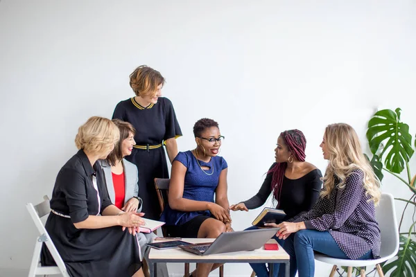 Pozytywne kobiety omawiają plan organizacji siedząc przy stole z laptopem — Zdjęcie stockowe