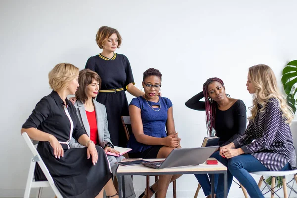 Mulheres positivas discutem plano de organização enquanto se sentam à mesa com laptop — Fotografia de Stock